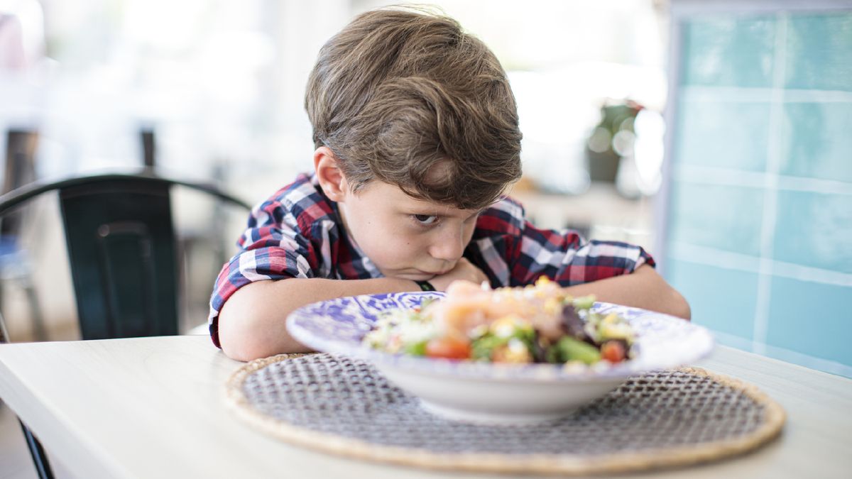 young boy refusing to eat his dinner