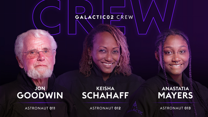 A white, grey-haired man with a beard, a smiling black woman, and a younger smiling black woman with facial piercings pose for the Galactic02 crew portrait.