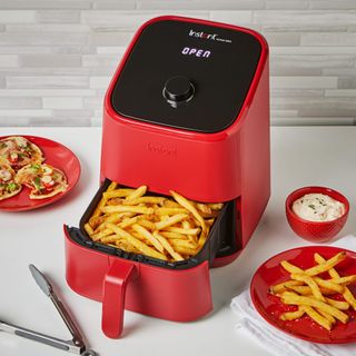 Red Instant air fryer with open drawer containing potato chips on white counter