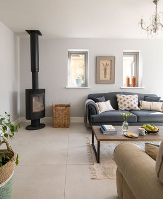 living room with gray sofa and woodburner in corner neutral walls