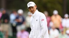 Min Woo Lee in a white cap and white jacket during a Masters practice round