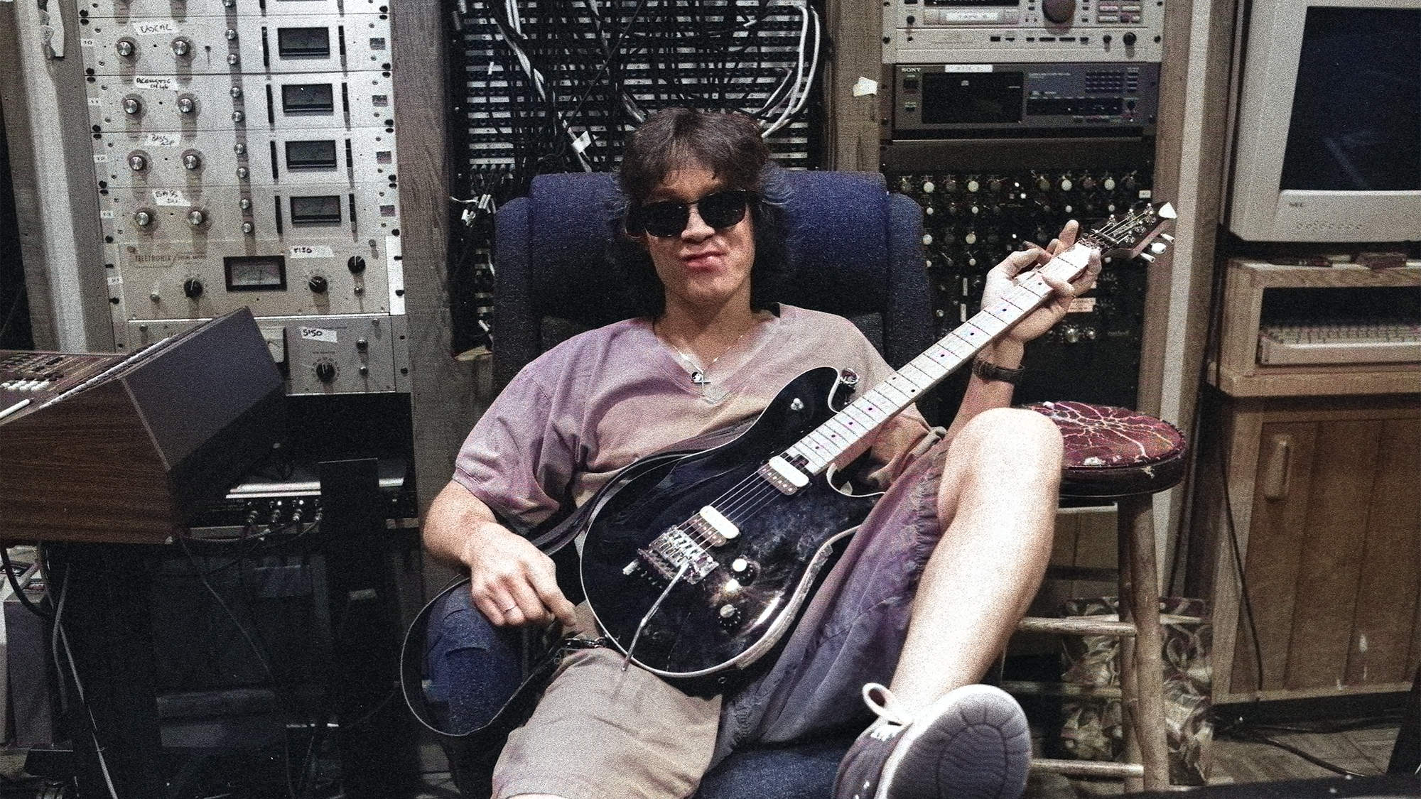 Eddie Van Halen holds a guitar while sitting in his 5150 recording studio in 1990.