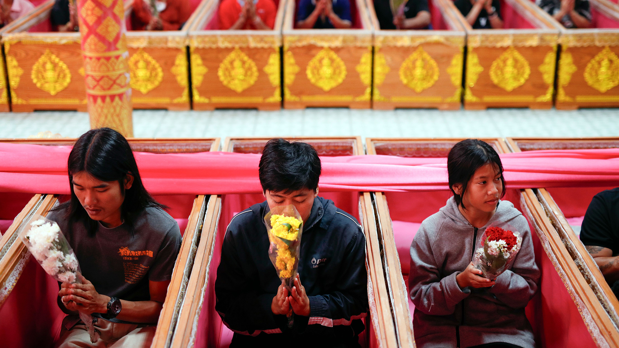 Buddhist devotees pray inside coffins during the New Year's resurrection ceremony at Wat Takien temple in Bangkok, Thailand