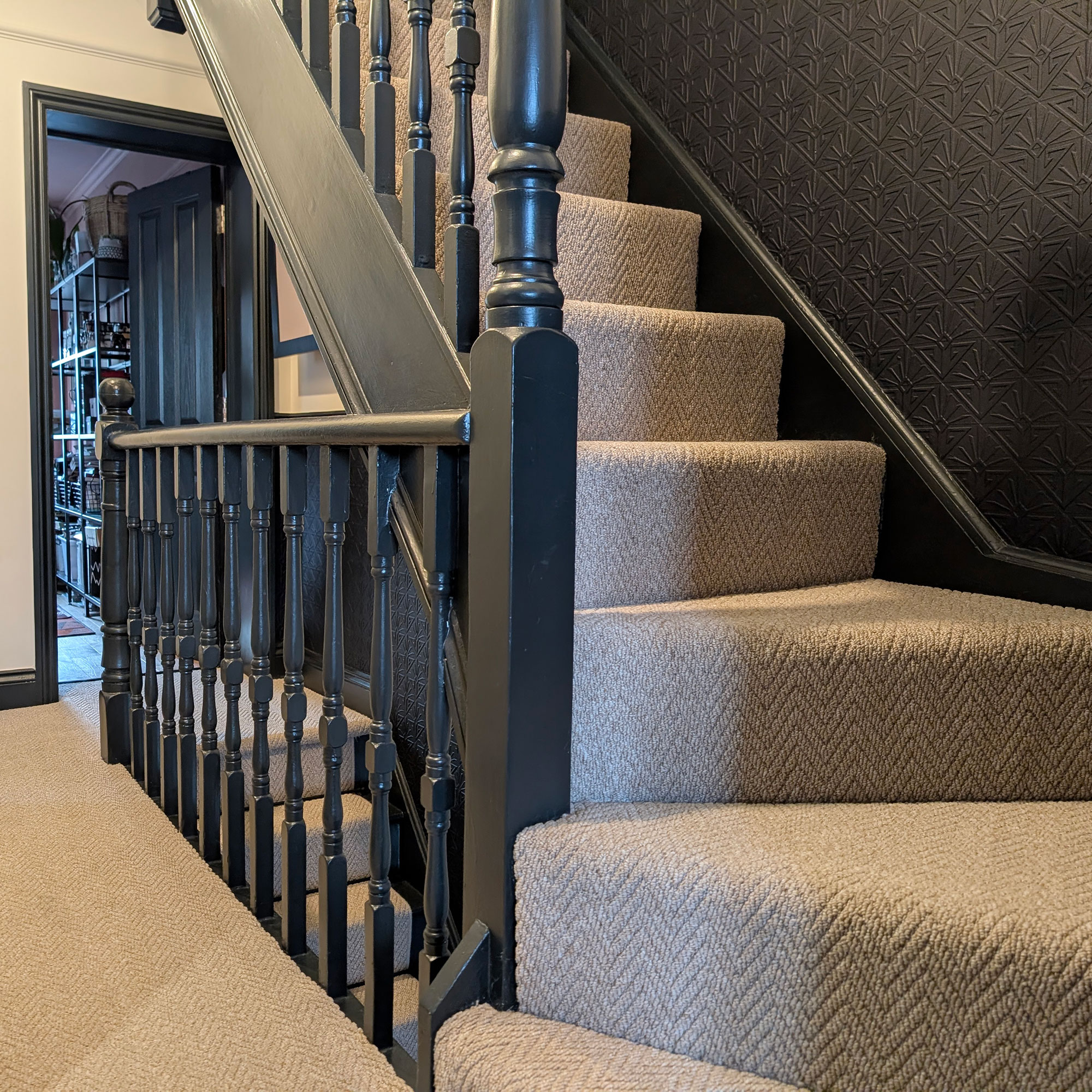 Landing in house with black walls and banisters and neutral carpet