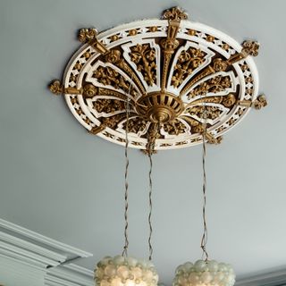 Intricate gold accent lighting fixture against light seafoam ceiling