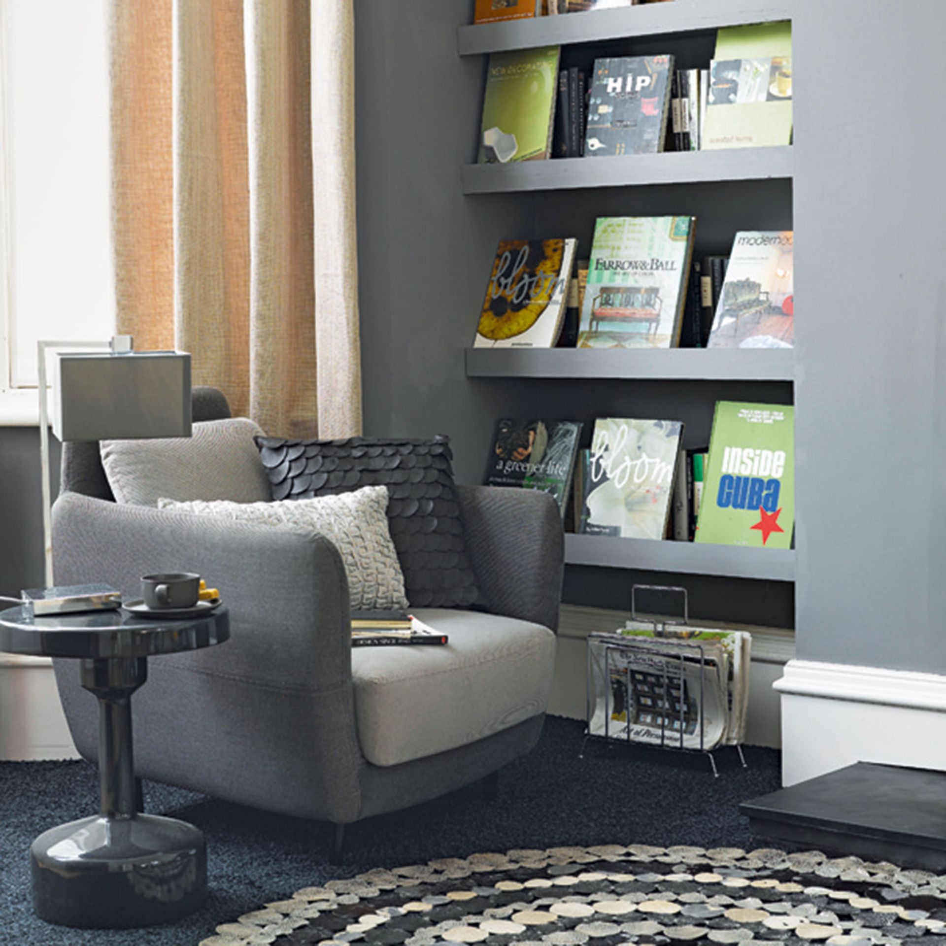 Armchair in a grey living room with open shelves and books on display