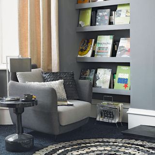 Armchair in a grey living room with open shelves and books on display