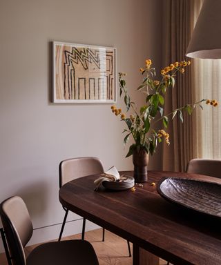 A Japandi-style dining room with art on the walls and a vase of flowers on the table