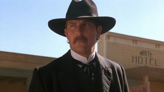Kevin Costner in a black hat and black suit in Wyatt Earp