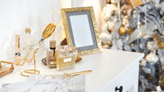 A vanity dresser covered in items including a photo frame, perfume and scissors