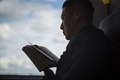 A person reading book with earphone connected