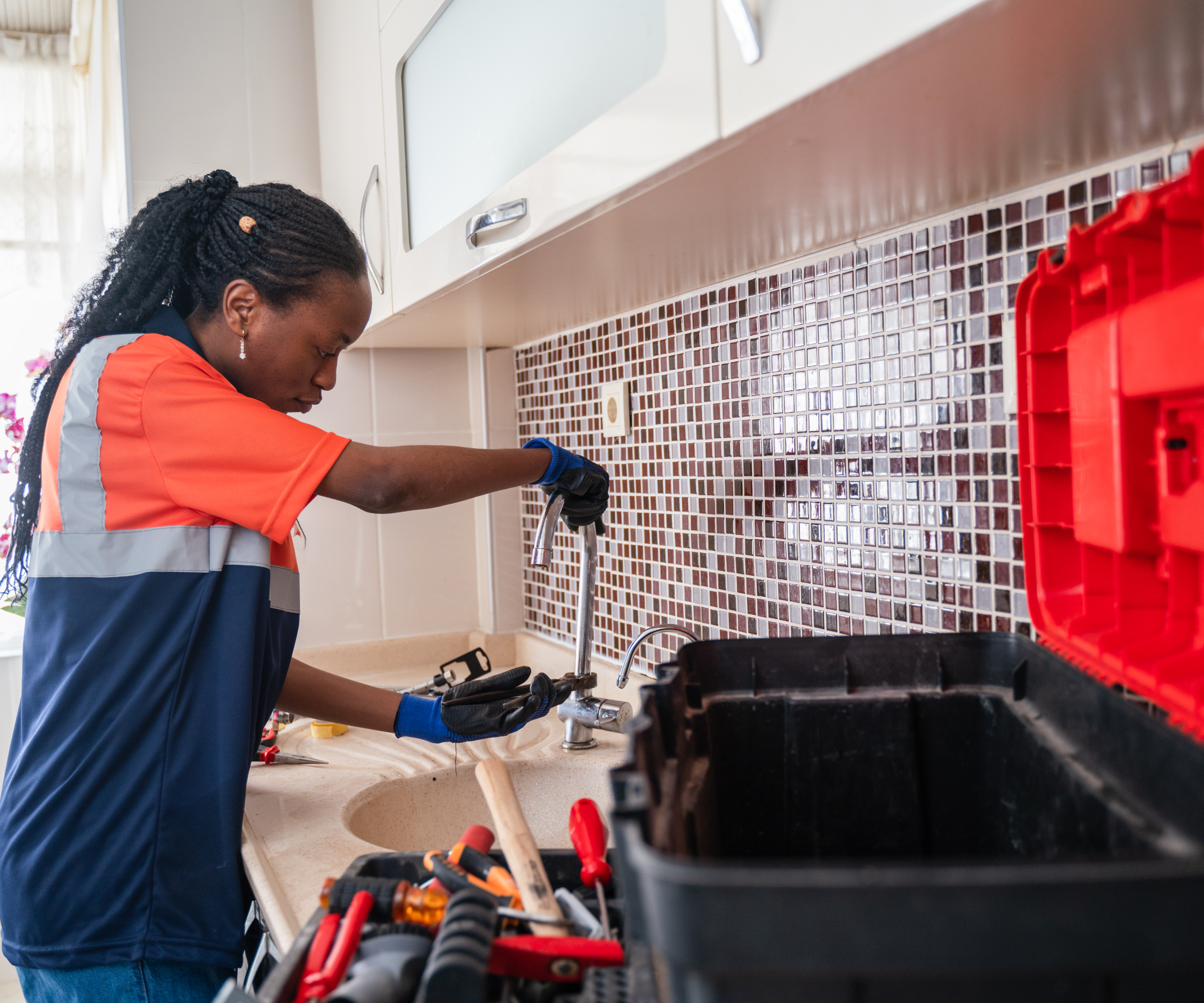 black female plumber working on kitchen sink and tap
