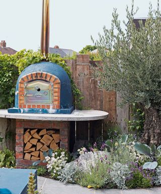 pizza oven in front of rustic wall made from garden sleepers