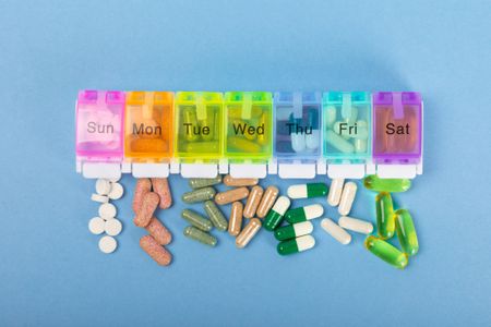 Vitamins and supplements. Variety of vitamin tablets in a jar on a texture background.Multivitamins with fresh and healthy fruits.Food supplements. Flat lay. Space for text.Copy space