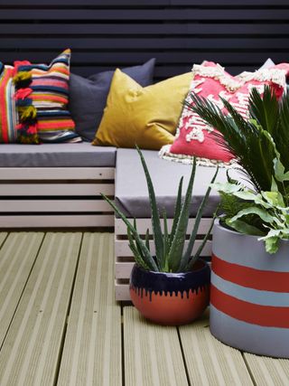 terracotta planters painted in bold colours and patterns in a modern colourful garden