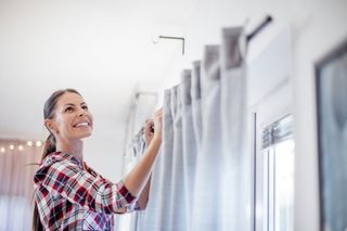 a woman putting up curtains