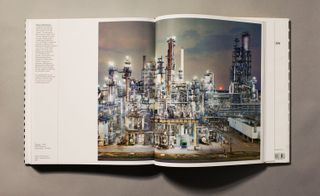 An open book with an image of a factory at night on both pages and a small amount of text down the left page.