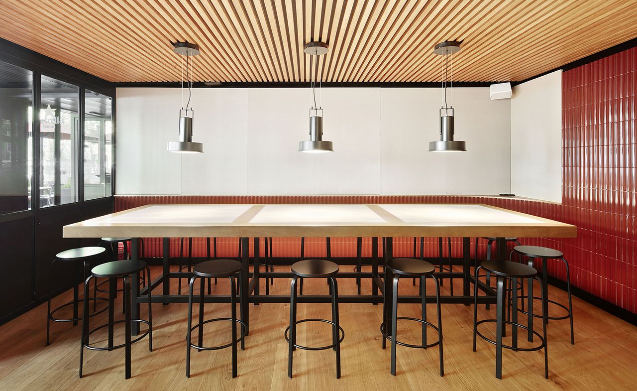 Large, long dining table with black stools