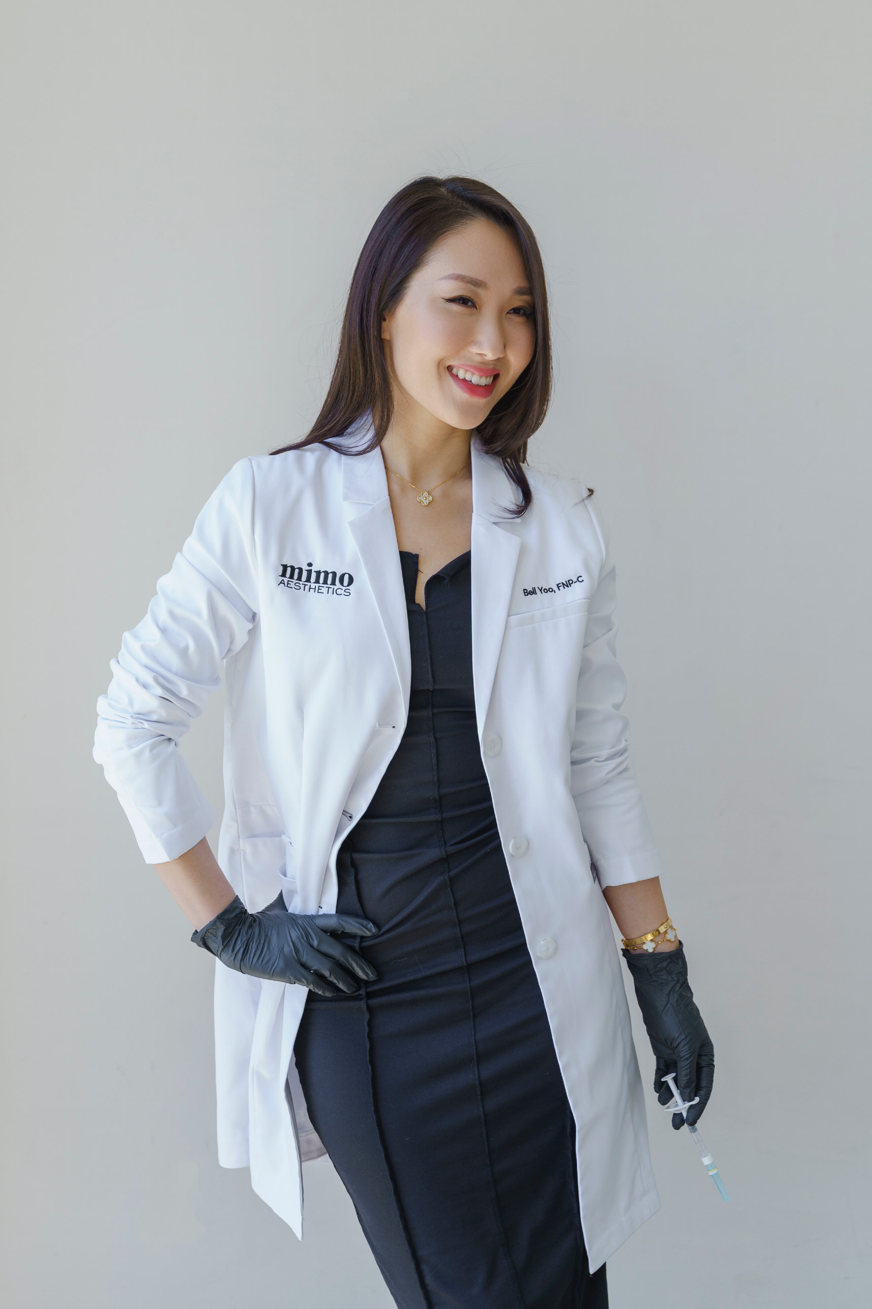 a young korean woman in a black dress, white lab coat, and black gloves