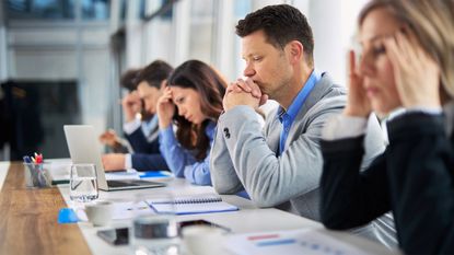 A row of businesspeople look serious in a meeting