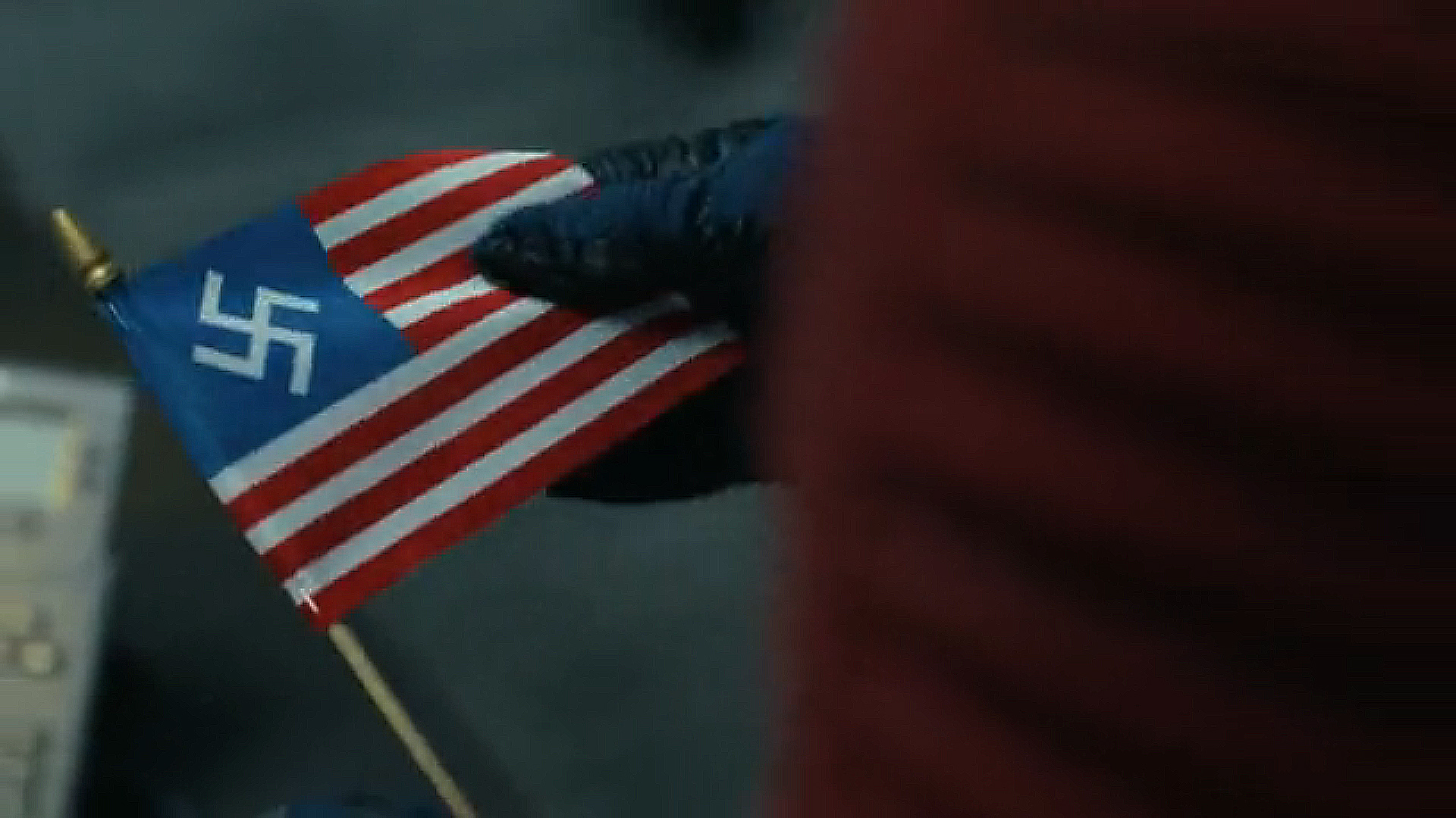 A close up of Chris Smith holding a US Nazi flag in Peacemaker season 2 episode 6