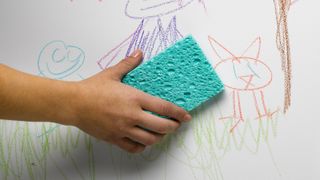 a sponge wiping away children's drawings on a wall