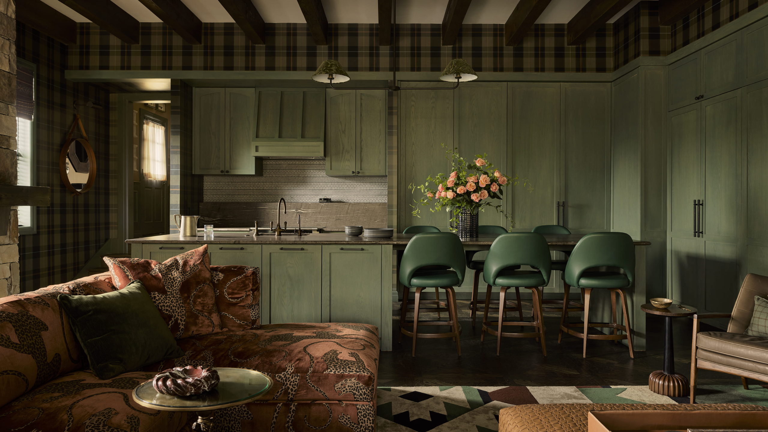 a green kitchen and living area with a velvet sofa and tartan wallpaper