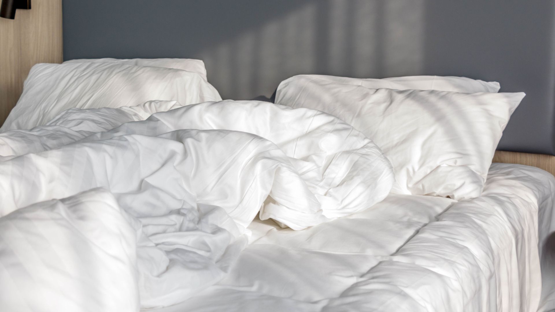 picture of unmade bed with white bedding