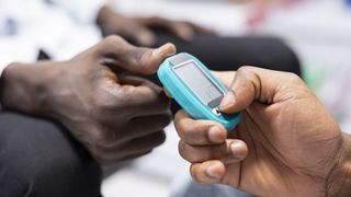 a close-up of someone passing a diabetes monitor to another person