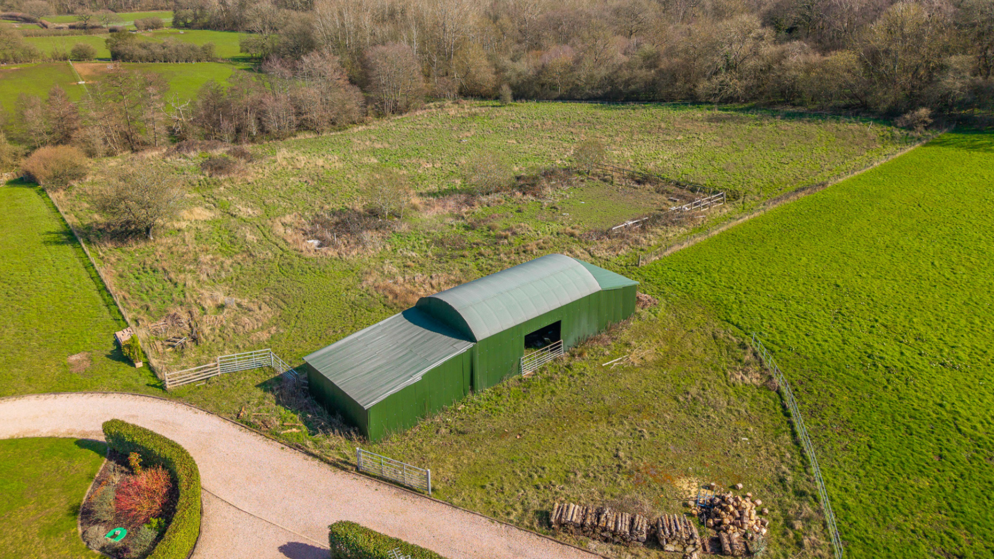 dutch style barn in a field with woodland to the back