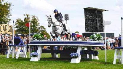 Holly Richardson and Ballyneety Silver Service clear a large white and blue table on the Defender Burghley Horse Trials 2025 cross-country course