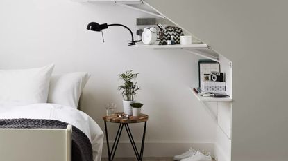 B&Q B&Q Goodhome Cleveland grey paint used in a bedroom with shelves, a bedside table and a bed