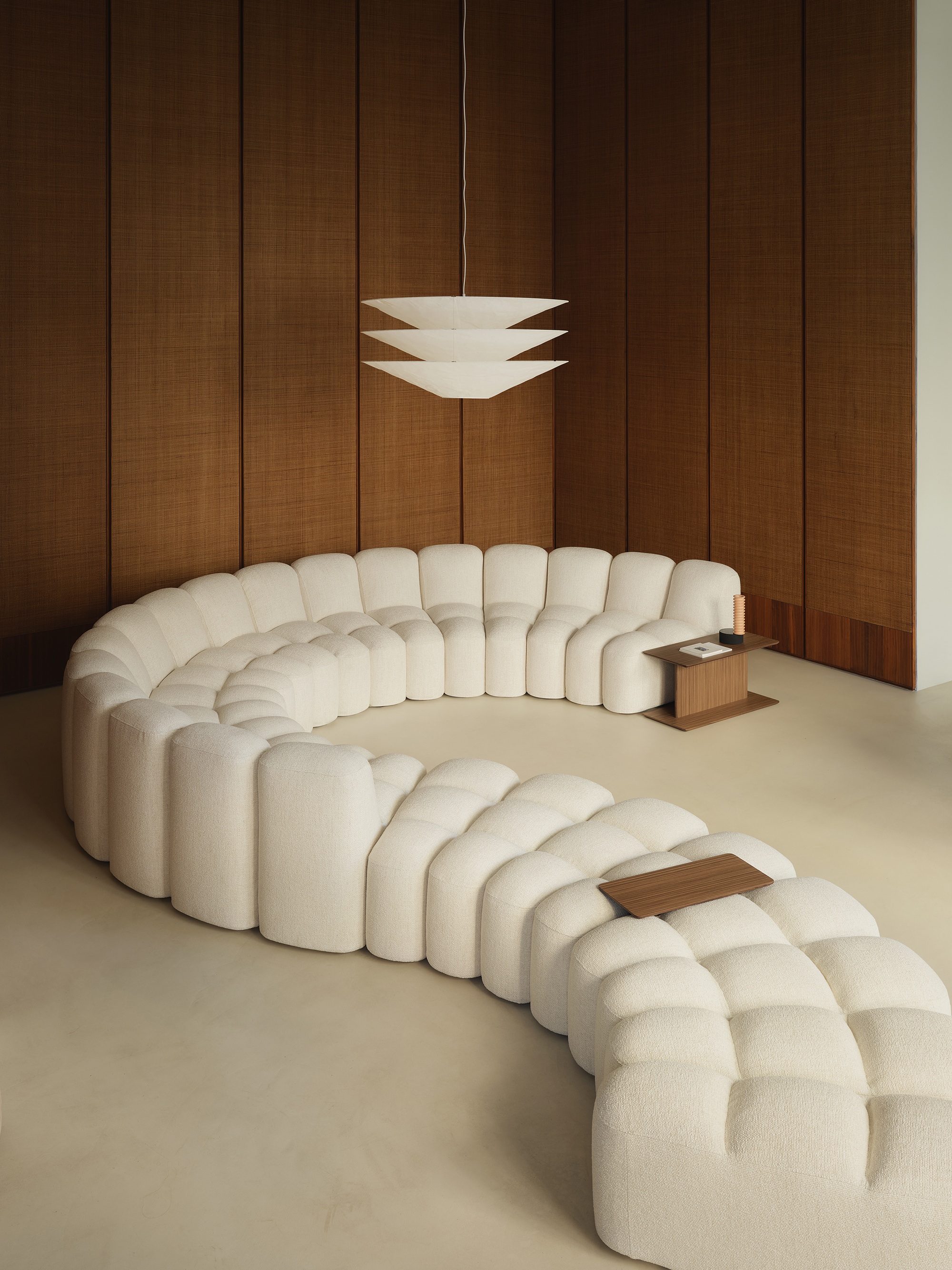a curved white modular sofa in a room with timber clad walls
