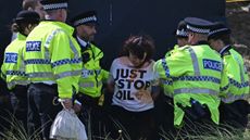 A woman wearing a 'Just Stop Oil' top being detained by police