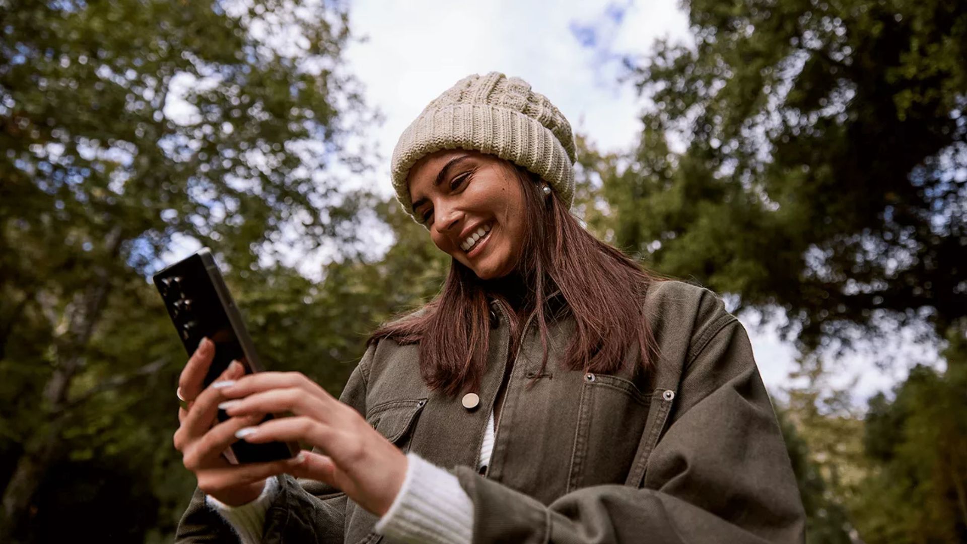 An image of a person holding an iPhone outside.