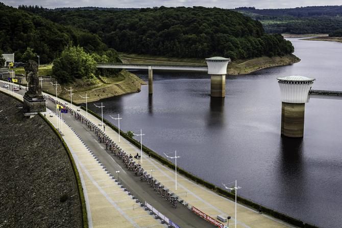 The peloton races over a bridge and scenic waterway