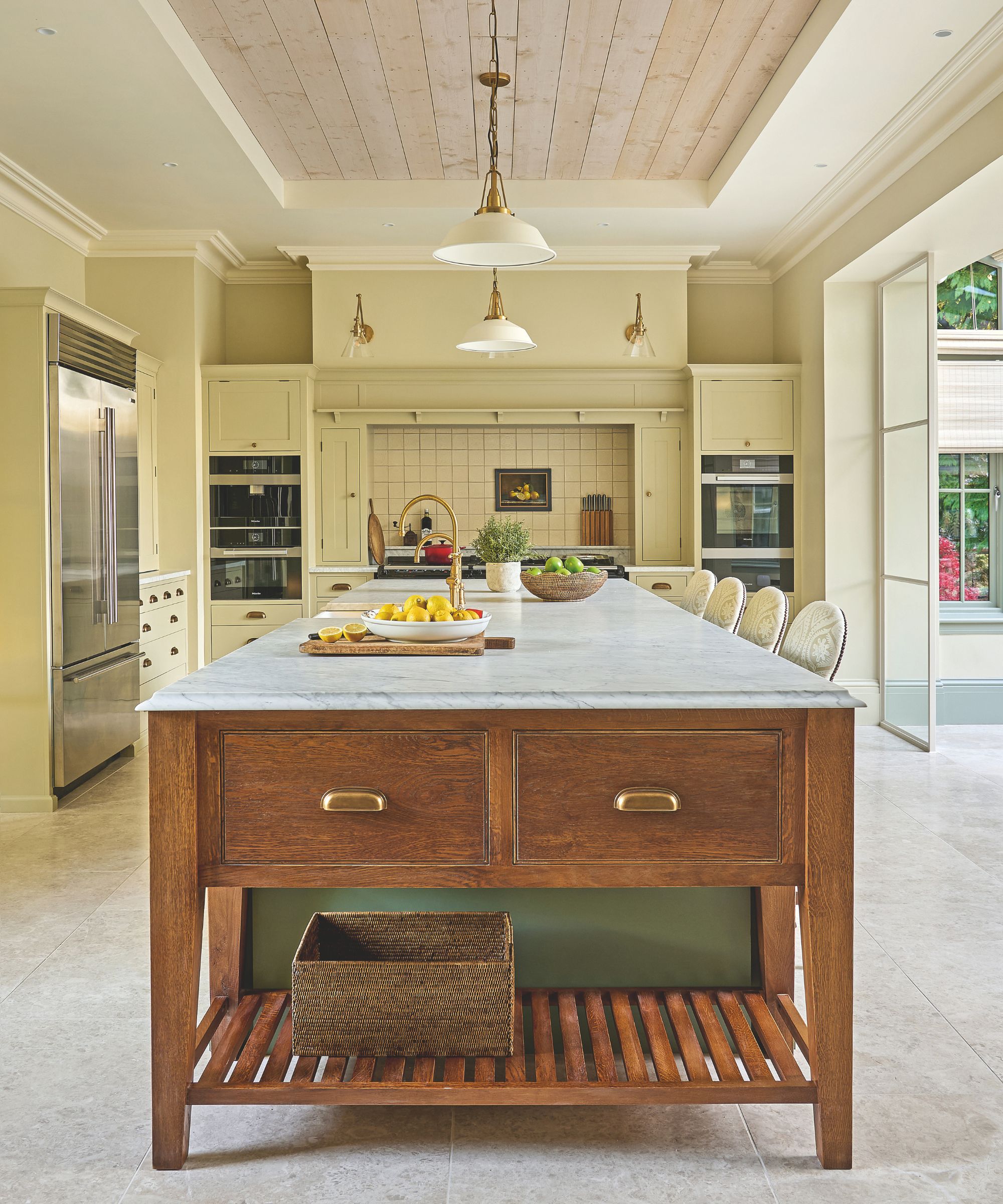 Pale yellow kitchen with large wooden island with a marble top