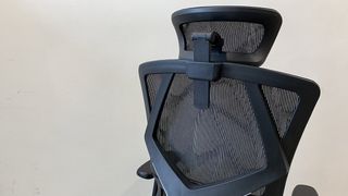 The back end of the SIHOO M90D office chair, positioned in a corridor.