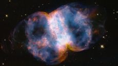 The Little Dumbbell Nebula, a colorful, barbell-shaped cloud of gas, as seen by the Hubble Space Telescope