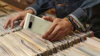 Google Pixel 7 Android phone held by a man browsing vinyl records in a store