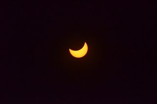 The moon turns the sun into an orange crescent during the partial phase of the April 8 total solar eclipse