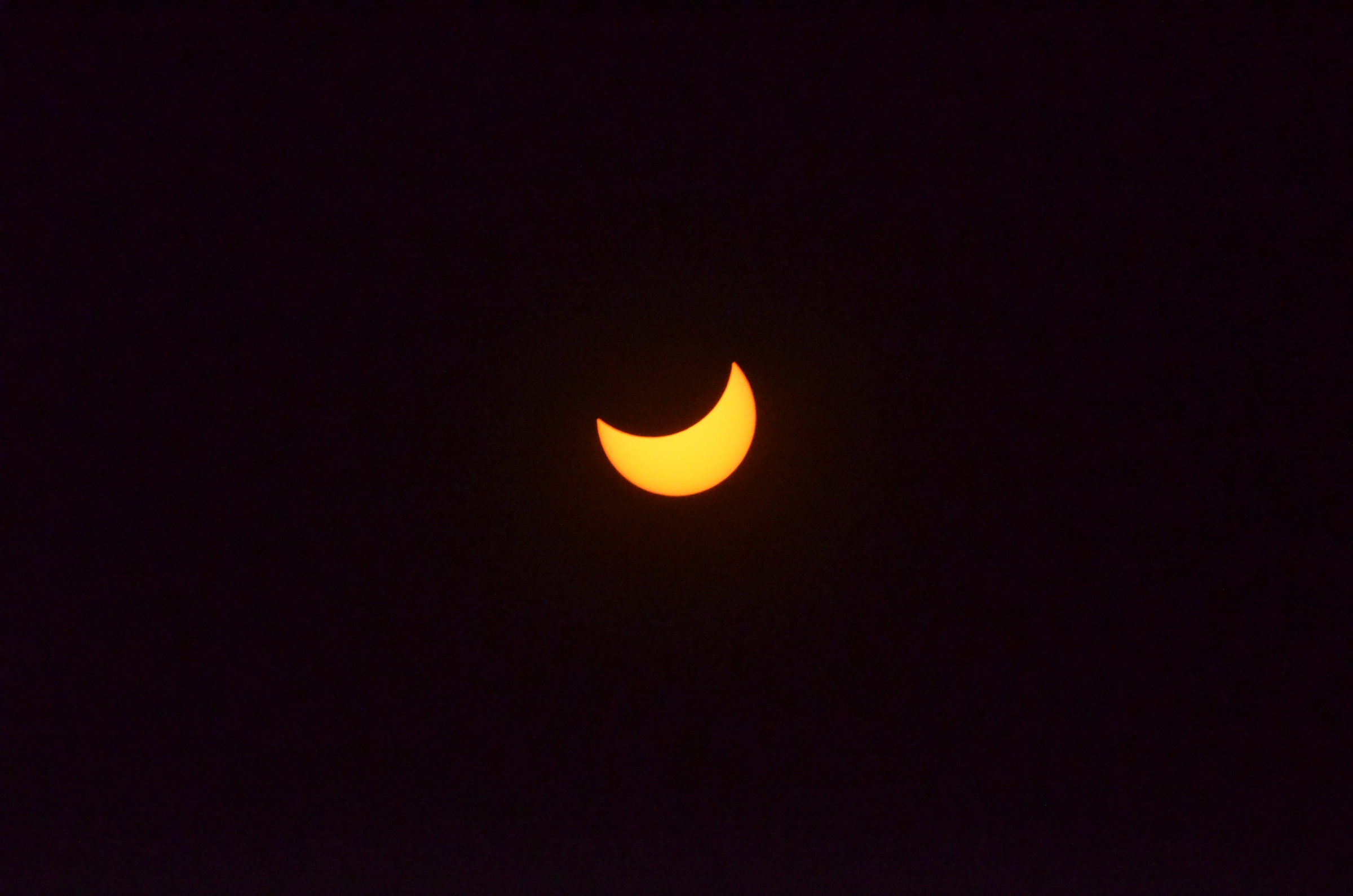 The moon turns the sun into an orange crescent during the partial phase of the April 8 total solar eclipse