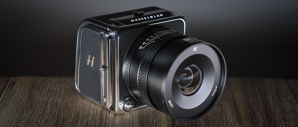 The Hasselblad 907X &amp; CFV 100C medium format camera with digital back, on a wooden table with artistic lighting