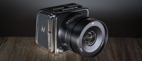 The Hasselblad 907X & CFV 100C medium format camera with digital back, on a wooden table with artistic lighting
