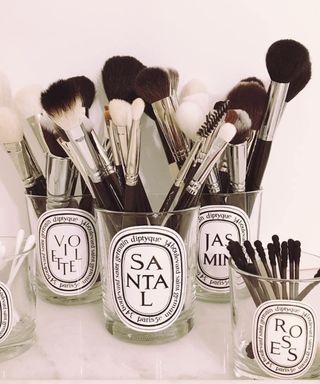An assortment of designer candle jars containing cosmetic make-up brushes