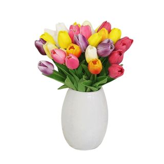 A white vase filled with colorful tulip flowers