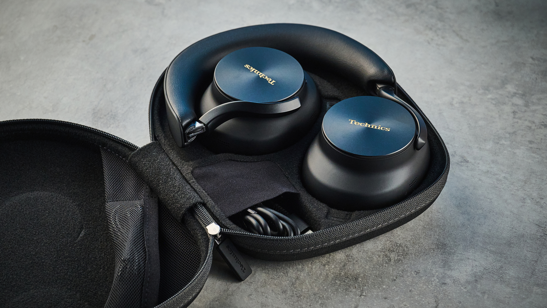 the technics eah-a1000 headphones with a gold technics logo photographed against a blue background