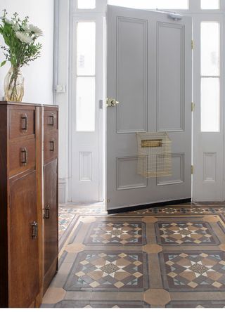 Inviting hallway with original victorian tiles and a wooden storage unit