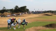Players and caddies walk down a fairway at the 2026 Open