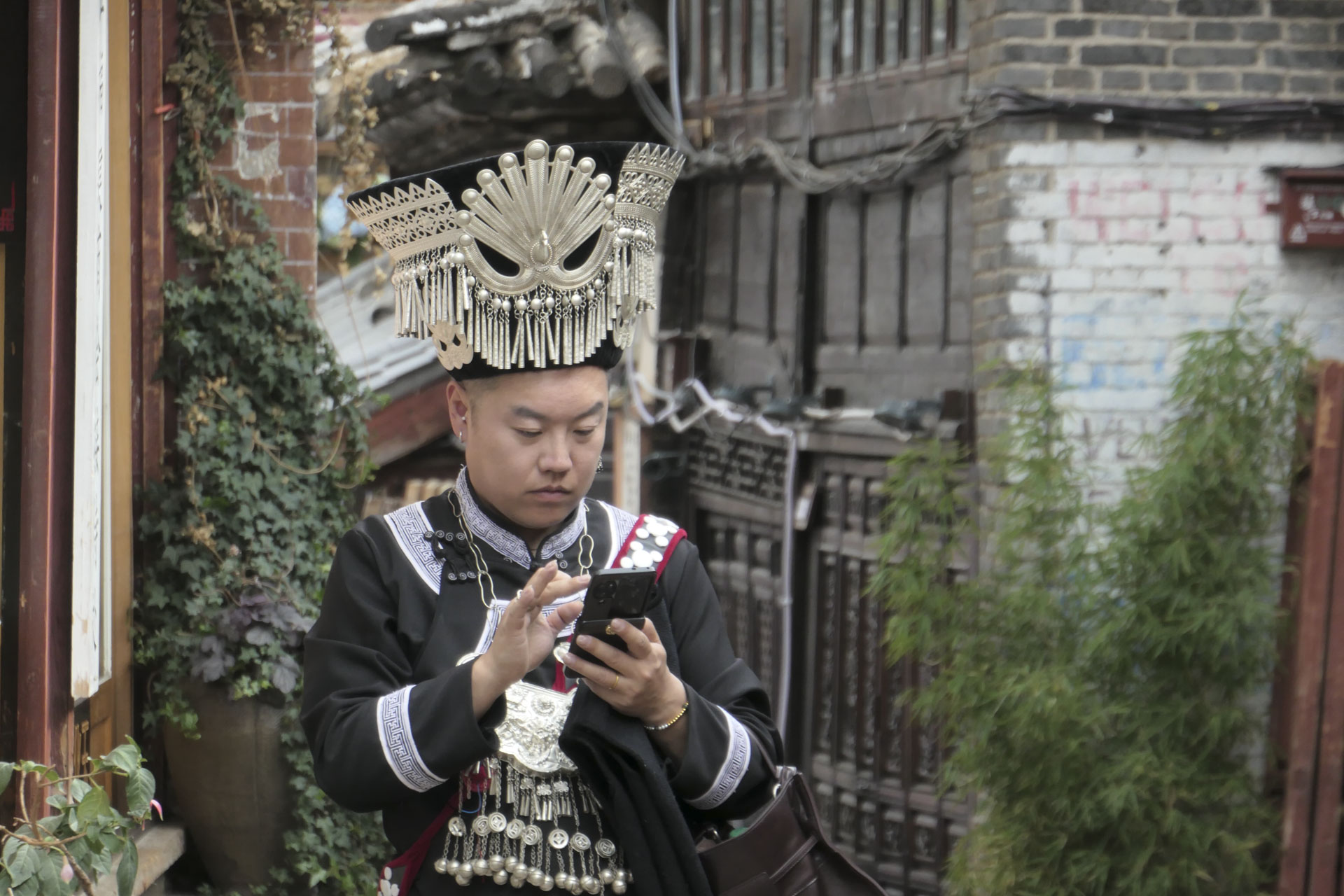 A man dressed in traditional Chinese attire, looking at his phone